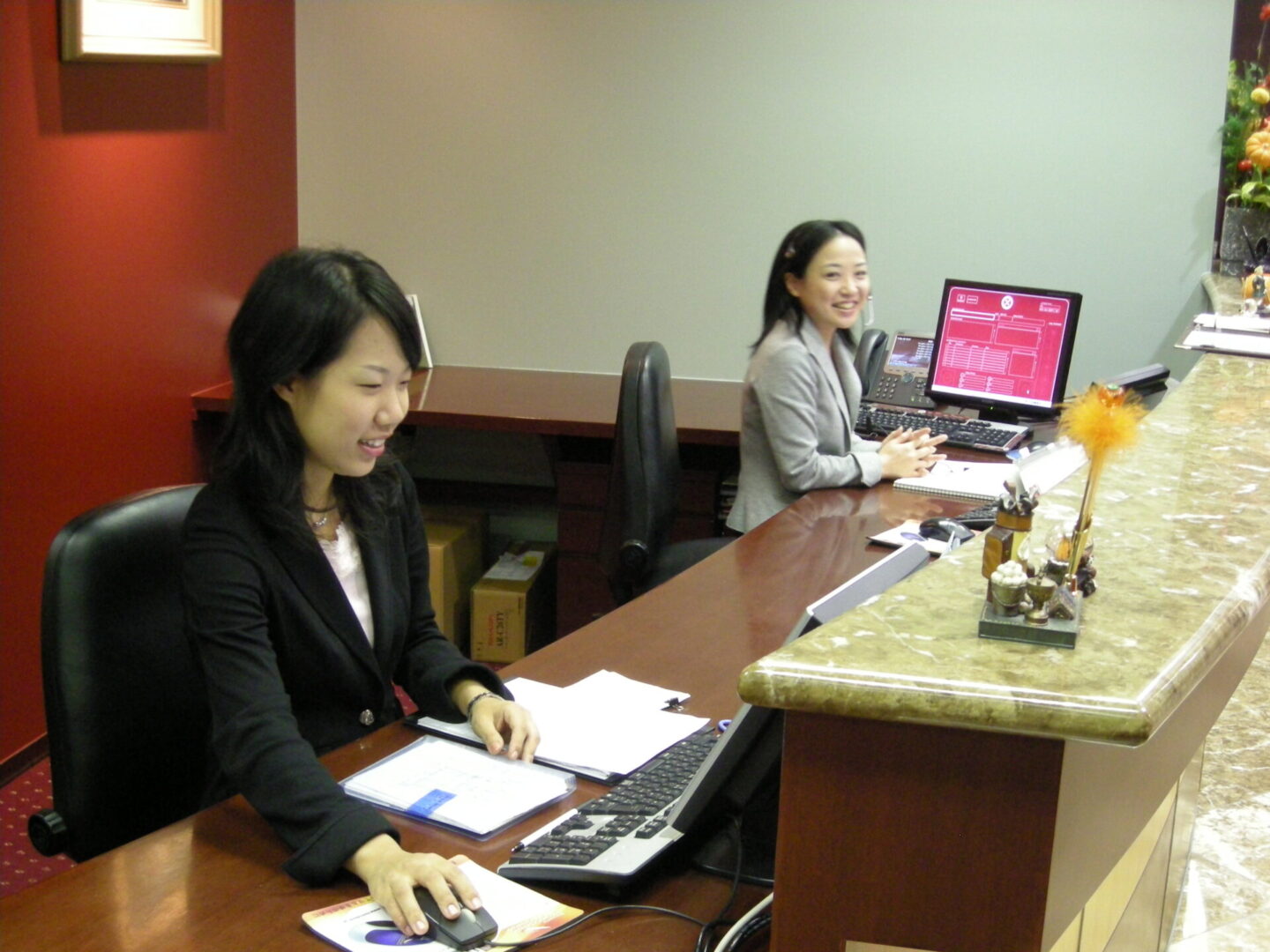 Two women sitting at a table with laptops.