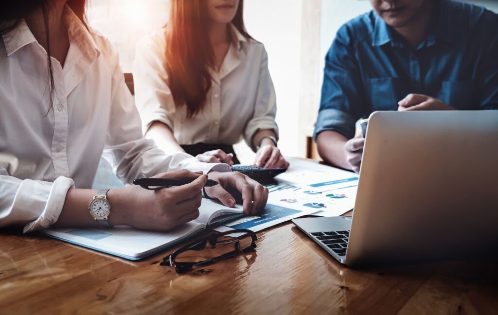 A group of people sitting around a table with papers.