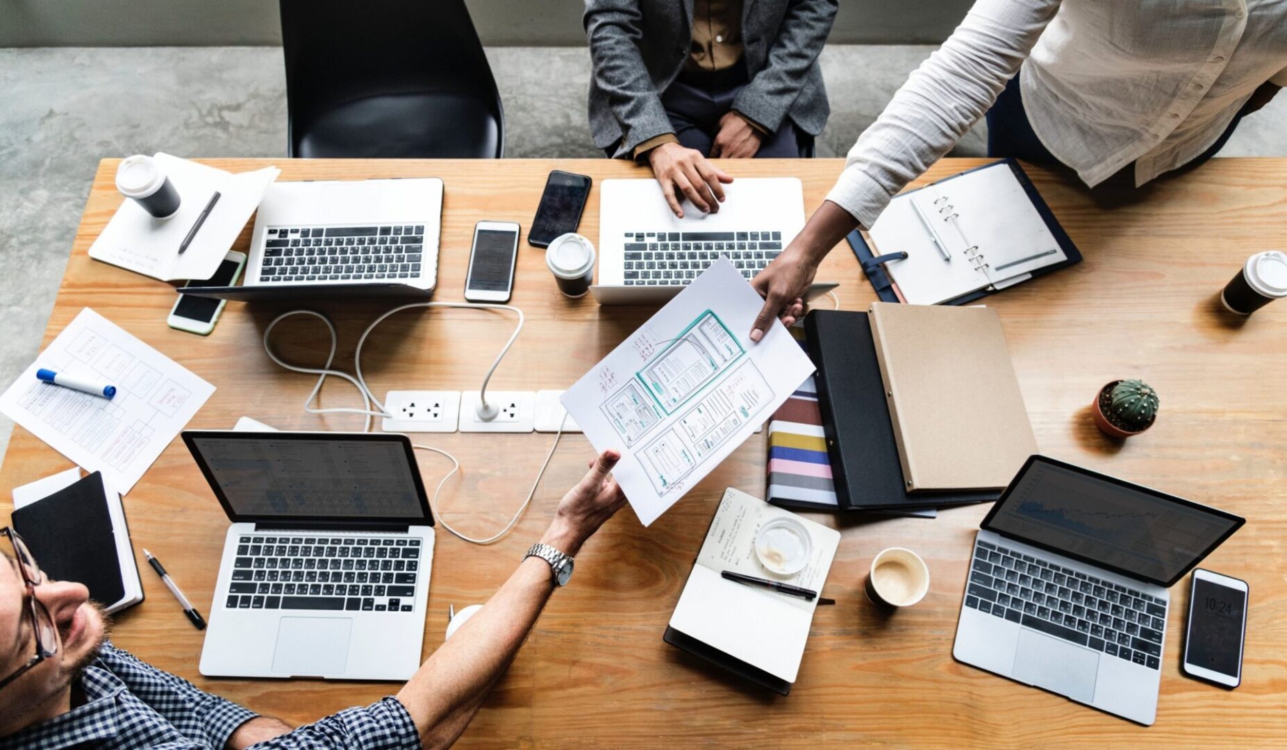 A group of people sitting around a table with laptops.