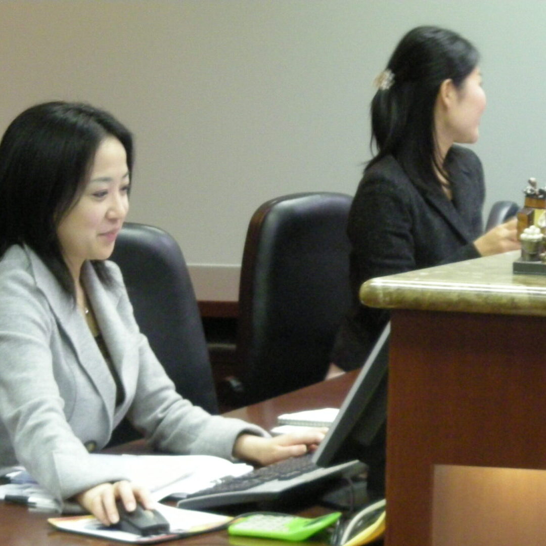 Two women sitting at a table with laptops.